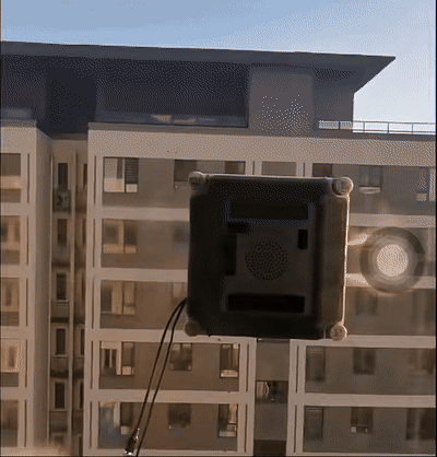 Square window cleaning robot in operation on glass